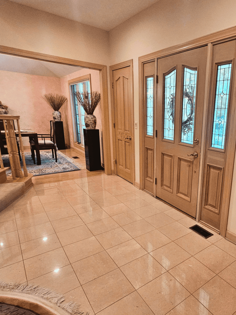Stylish door entry with decorative glass design, ceramic tile flooring, and elegant wooden trim accents.