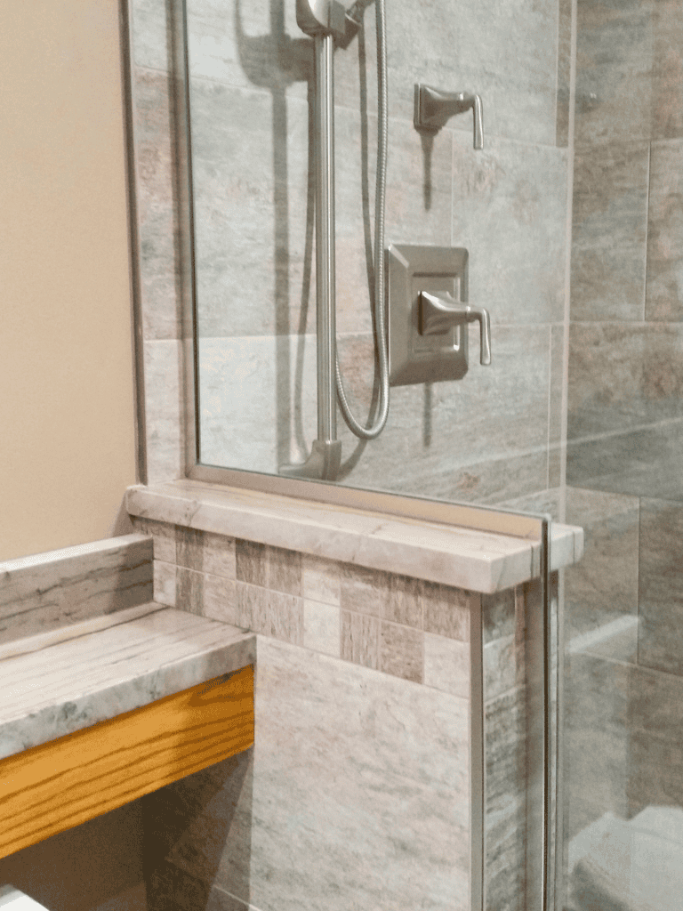 High-quality custom shower design with stone tiles, glass panels, and modern fixtures.