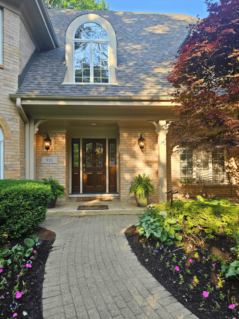 High-quality custom home exterior with brick façade, lush landscaping, and inviting entrance design.
